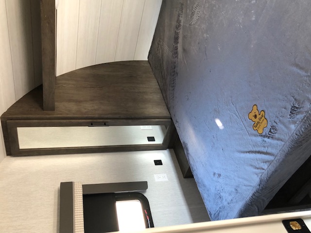 Compact RV rental bedroom with 'Teddy Bear' mattress, built-in corner storage, and power outlets.. Forest River Salem 2022
