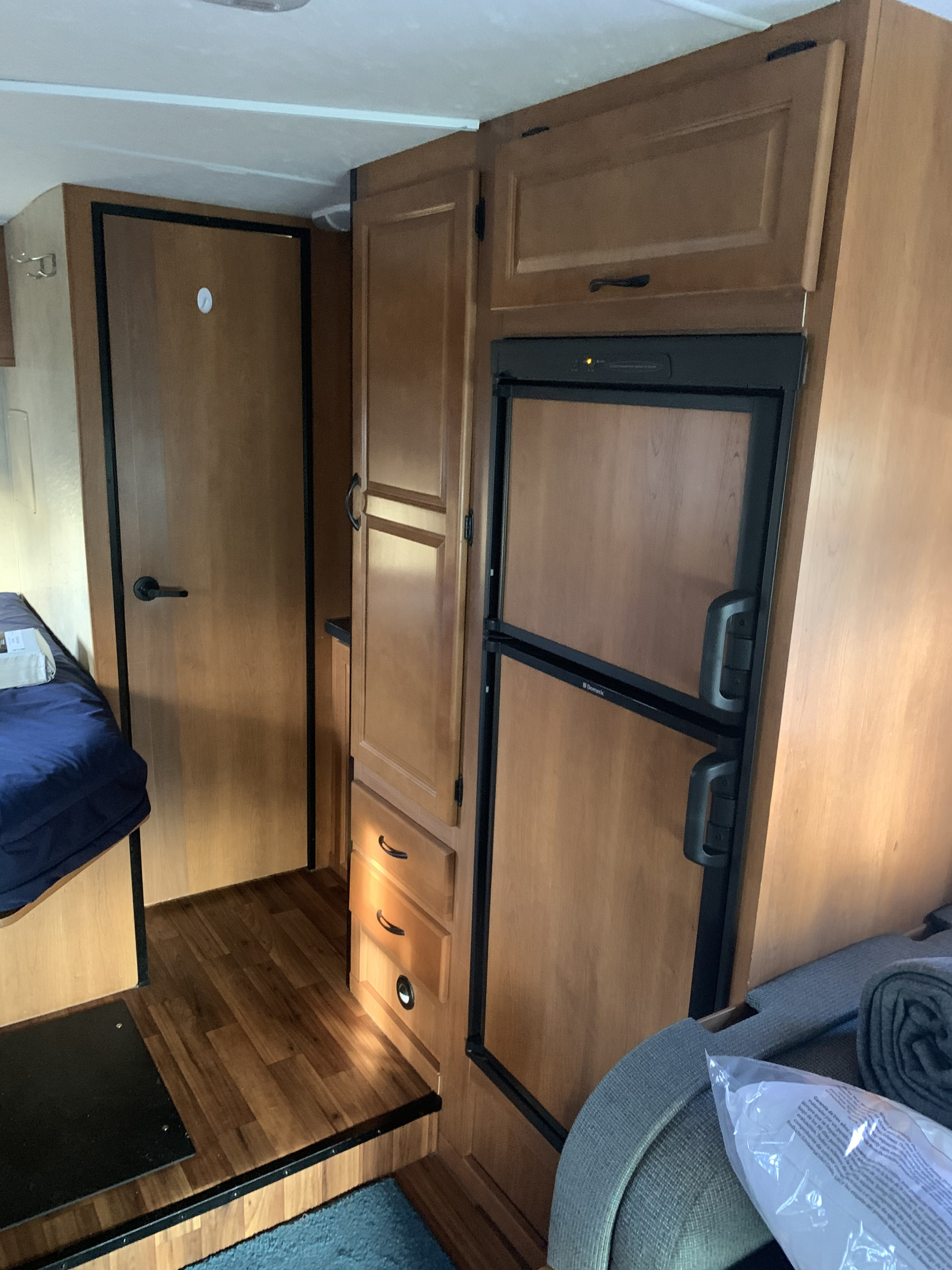 RV rental interior: wood cabinetry, Dometic refrigerator, bed area, and living space with wood flooring.. Thor Motor Coach Four Winds Majestic 2014