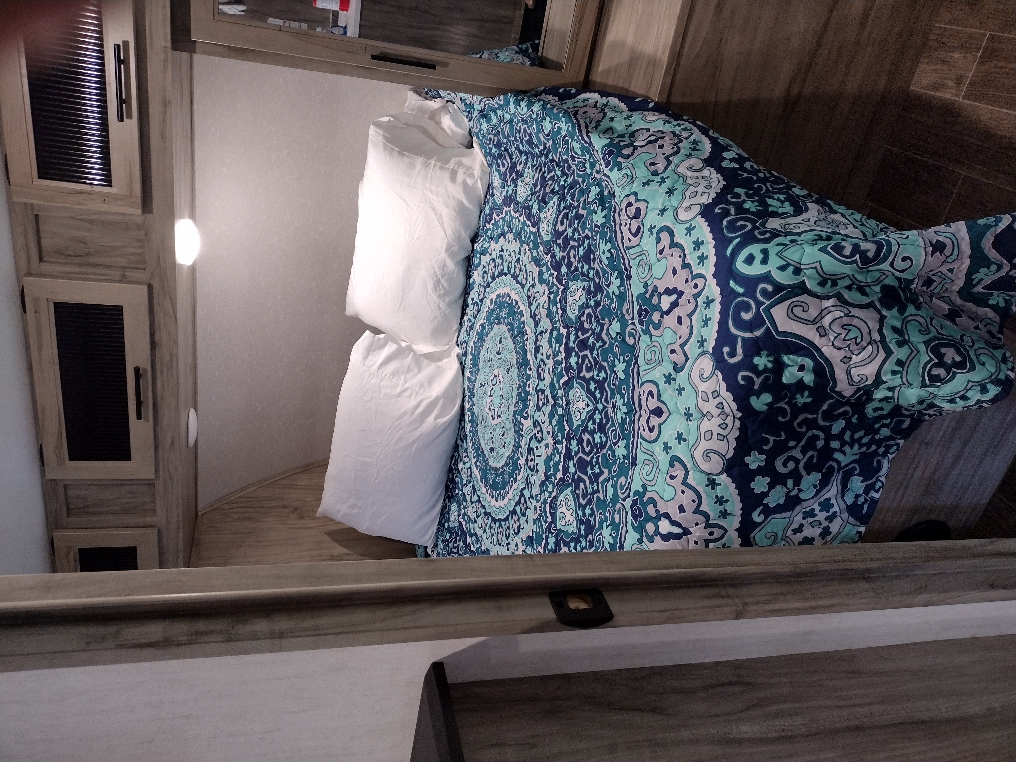 Experience comfort in this RV rental's bedroom, featuring a vibrant patterned comforter and ample storage cabinetry.. Forest River Cherokee Alpha Wolf 26 dbhl 2021
