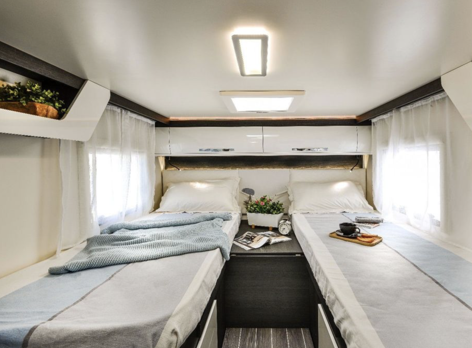 RV rental interior: a modern twin-bed sleeping area with overhead storage, ambient lighting, and sheer curtains.. Roller Team 685 Zefiro 2022