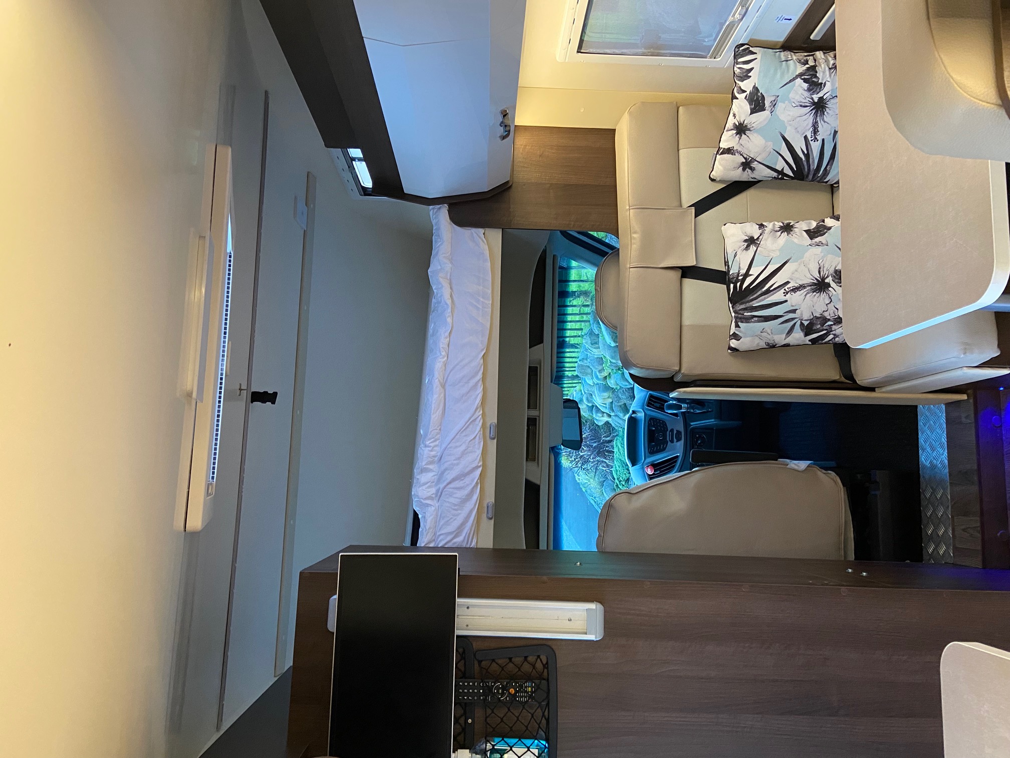 Explore this RV rental: A well-appointed camper interior featuring a bed, comfortable lounge seating, and driver's cabin view.. Ford Rollerteam Zefiro 690 2018