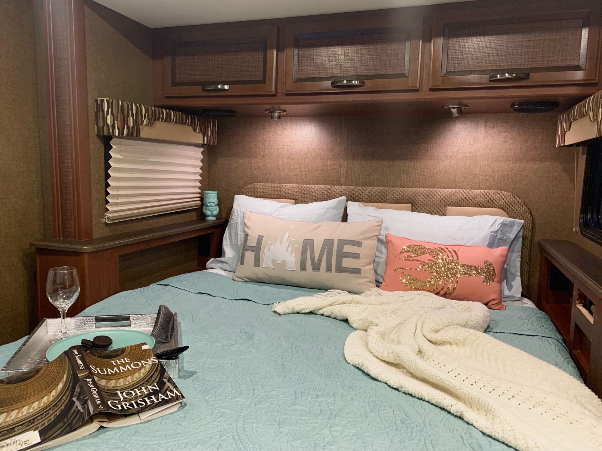 Cozy RV rental bedroom featuring a quilted bed, comfy pillows, a book, wine, and snacks for relaxation.. Thor Vegas 2016