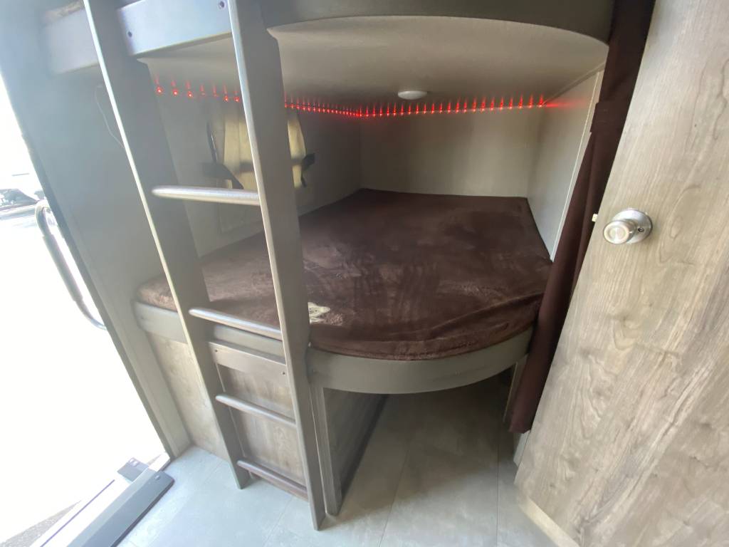 Cozy RV rental interior featuring bunk beds with a ladder, brown bedding, and ambient red LED lighting for your comfort.. Coachmen Other 2021