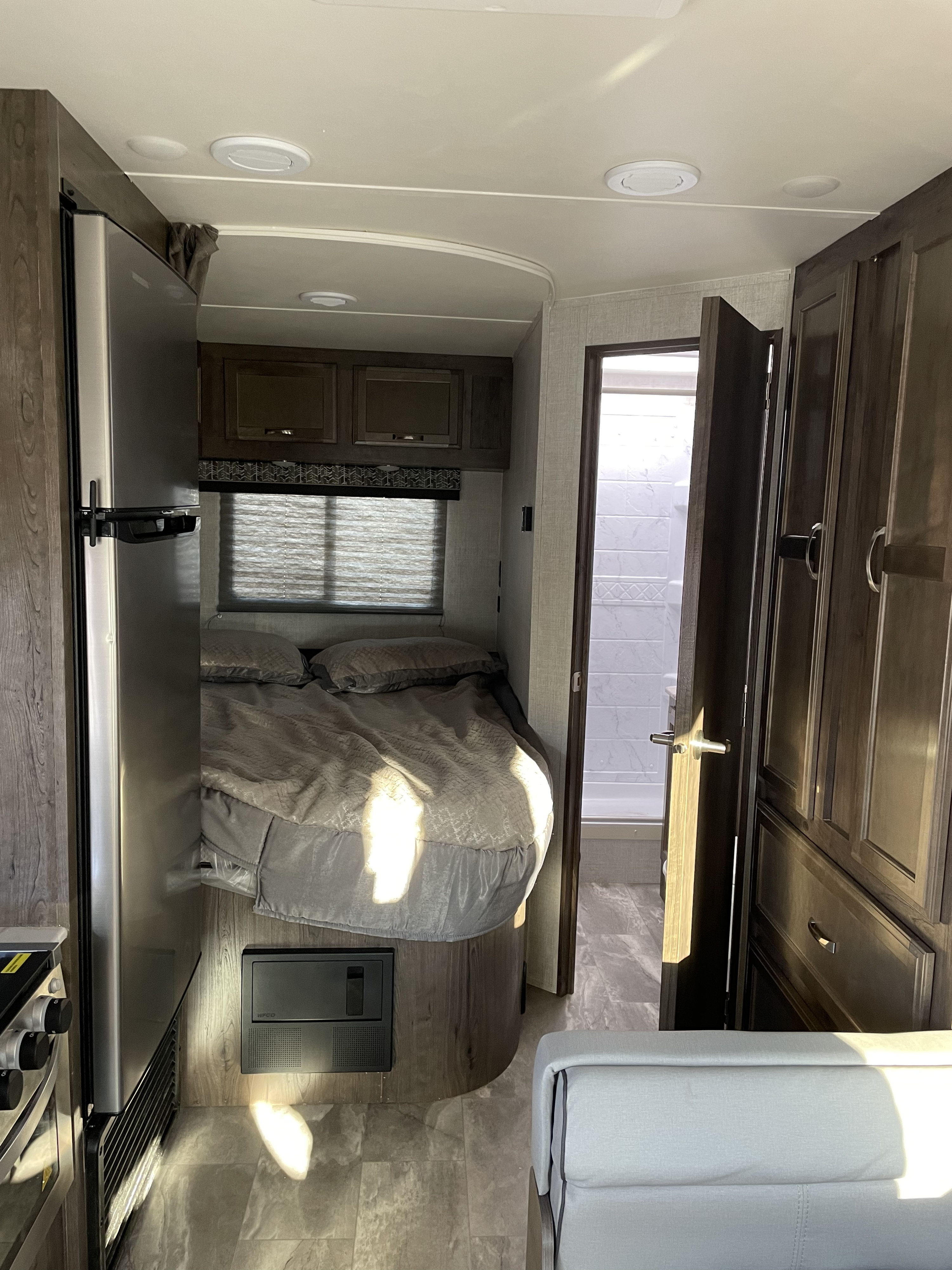 RV rental interior: inviting bedroom, compact kitchen with fridge, and bright bathroom. Your comfortable home on wheels.. Gulf Stream Conquest 2021