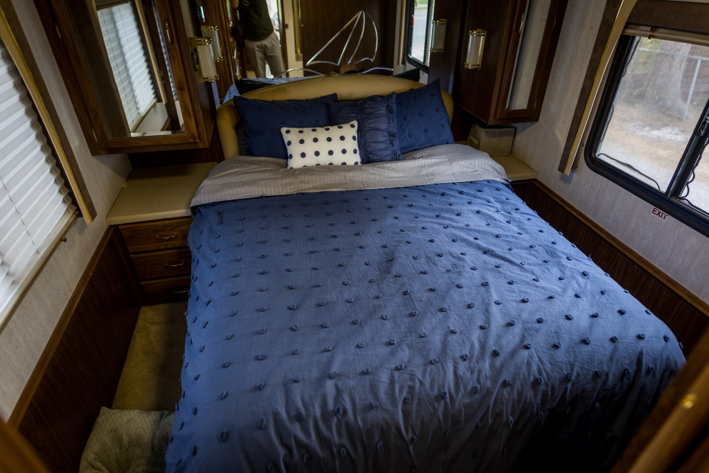 Cozy RV rental bedroom with blue bedding, sailboat decor, and compact storage.. National RV Tradewinds 2000