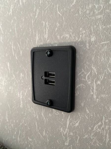 RV rental interior shows a wall-mounted black USB charging station with two ports for convenient device charging.. Forest River Cherokee Grey Wolf 2022