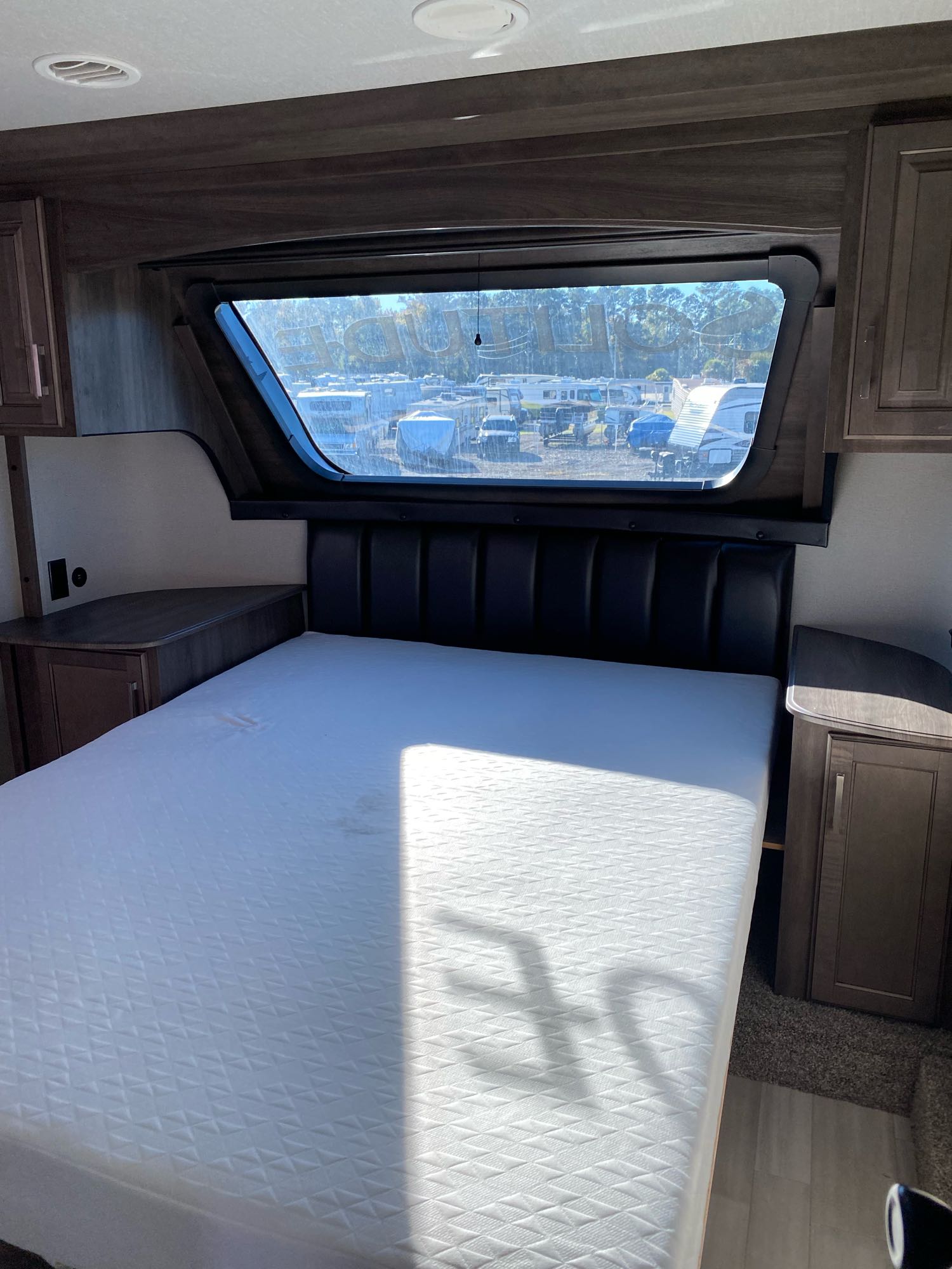 RV rental: Spacious, comfortable bedroom interior with a large bed, padded headboard, and window view.. Grand Design Solitude 2021