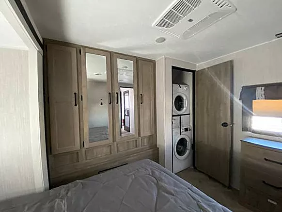 RV rental bedroom with mirrored wardrobe, stacked washer/dryer, and comfortable bed for your trip.. Palomino Puma 31-RLQS 2022