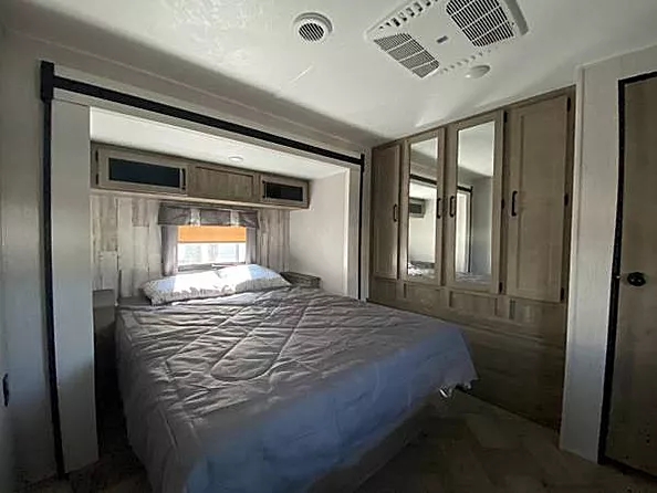 RV rental bedroom: a cozy space with a bed, overhead cabinets, mirrored wardrobe, and AC, ready for your comfortable travels.. Palomino Puma 31-RLQS 2022
