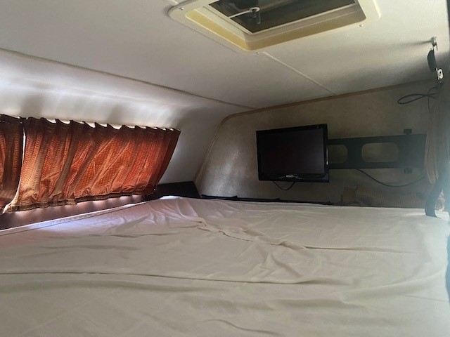 Enjoy cozy comfort in this RV rental's sleeping area, featuring a mounted TV and bed.. Coachmen Leprechan 2017