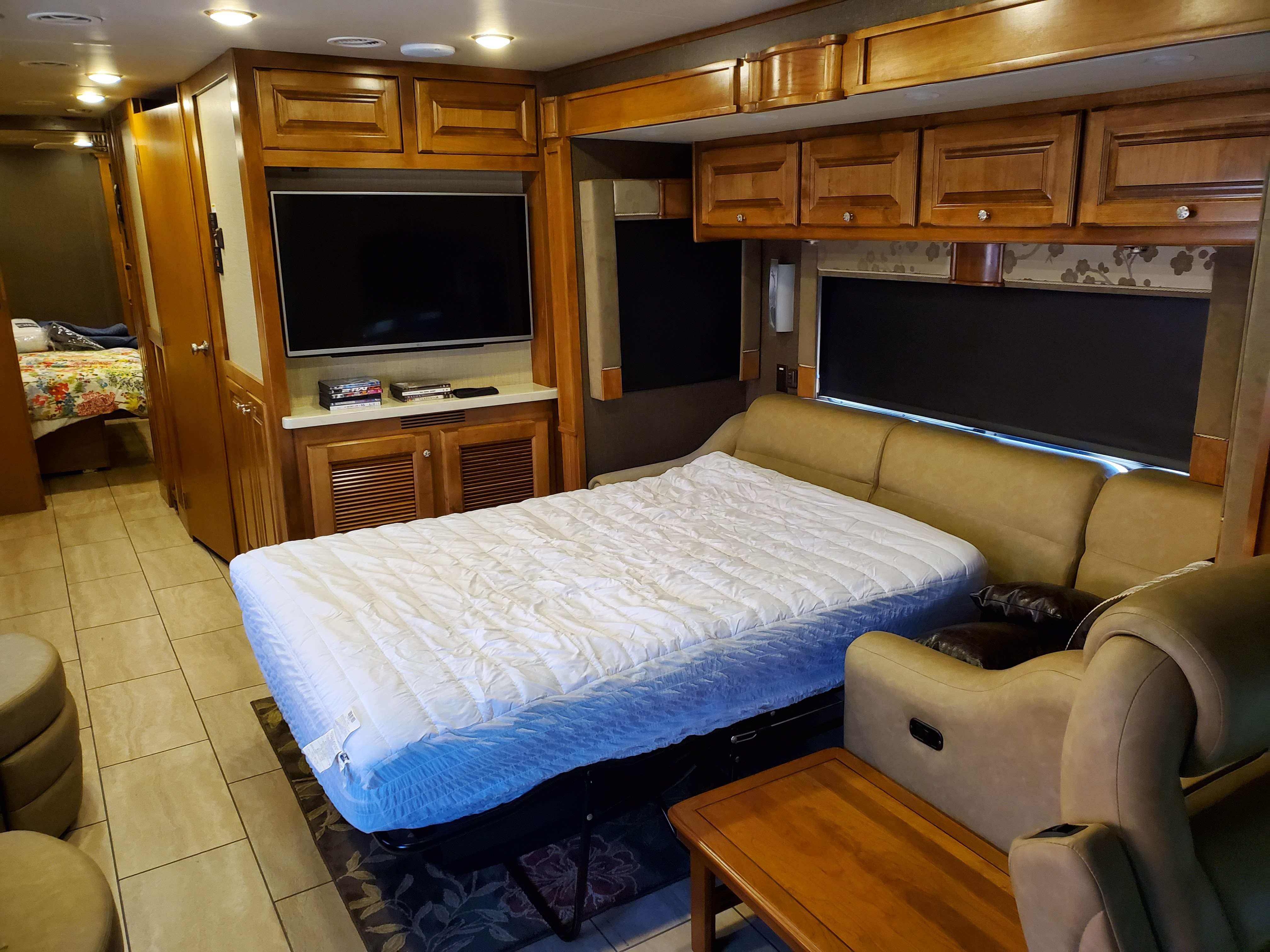 Spacious RV rental interior featuring a pull-out bed, sofa, TV, and elegant wood cabinetry.. Tiffin Motorhomes Allegro Open Road 2016