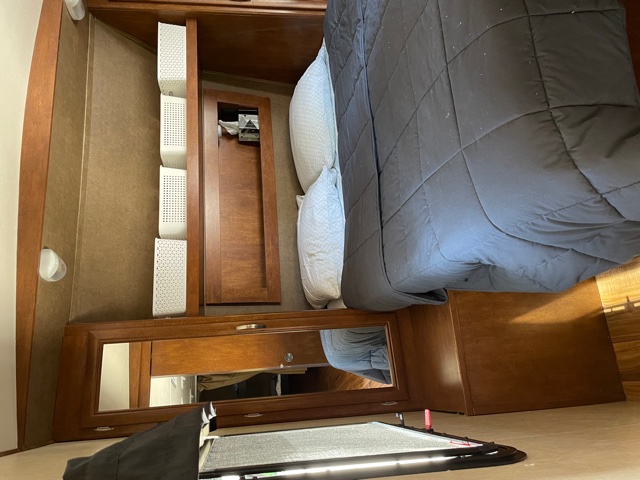 RV rental bedroom with compact storage solutions, a dark comforter on the bed, and warm wooden interior.. Forest River Vibe Extreme Lite 2016