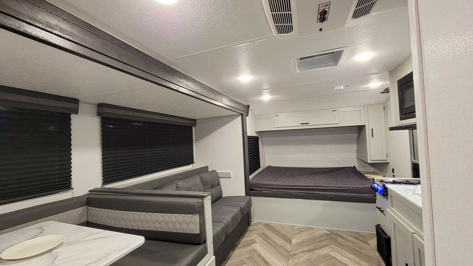 Spacious RV rental interior featuring a dinette, comfortable bed, and compact kitchen with a stove. Ideal for travel.. Forest River Wildwood FSX 2021