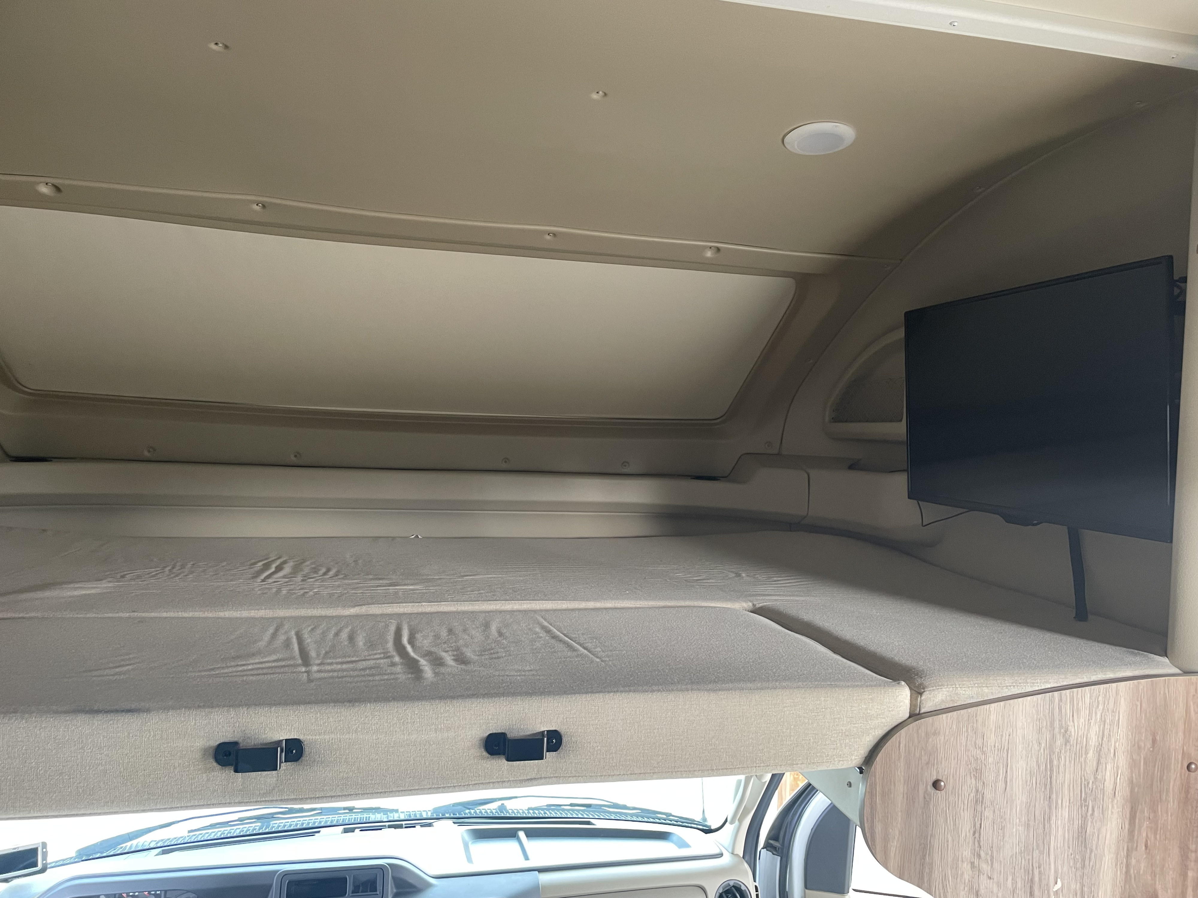 Full size bed over drivers cab with overhead window closed. This is where one of the TV's is located. It can be pulled out.. Entegra Coach Odyssey 2019
