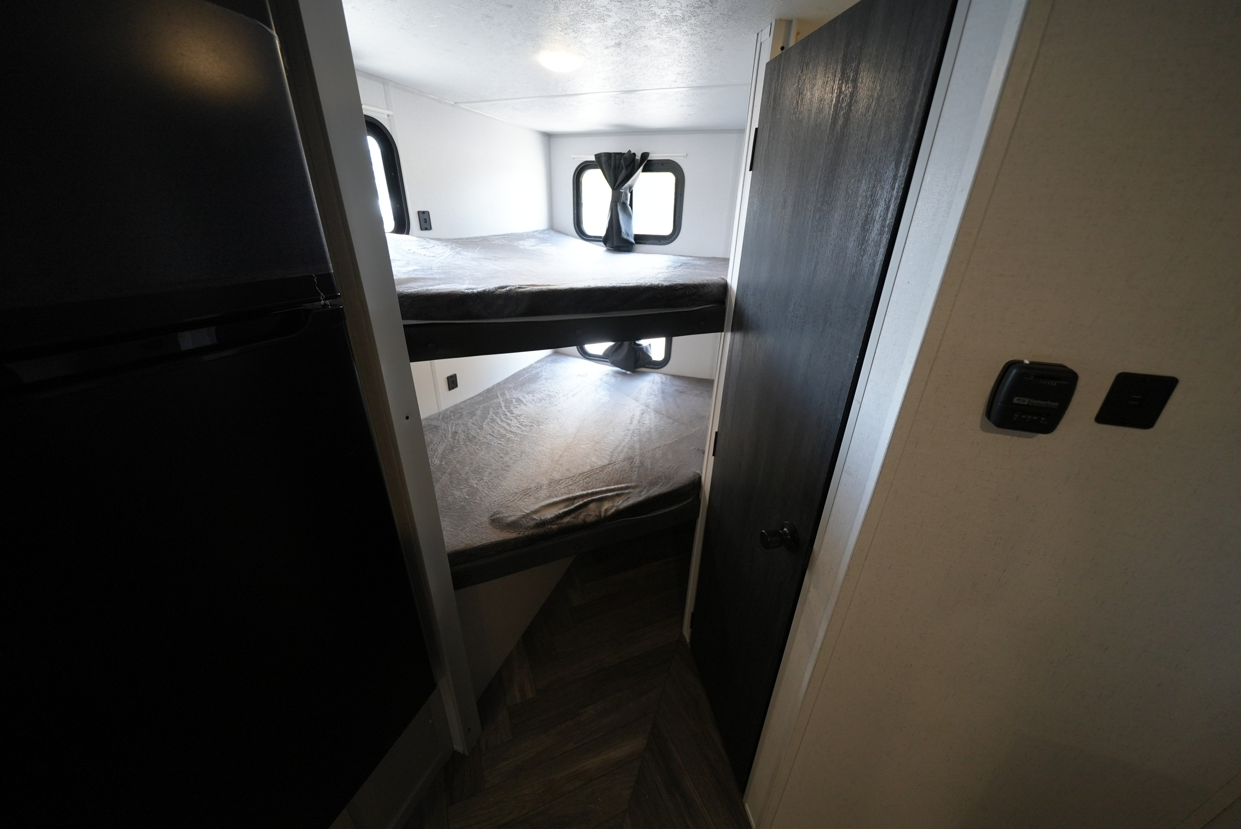 RV rental interior with stacked bunk beds, windows, and dark curtains. A functional and cozy sleeping area for travelers.. Forest River Wildwood FSX 2022