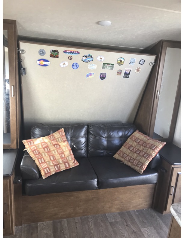 Explore the comfortable rv rental interior featuring a cozy black sofa and wall covered in memorable travel stickers.. Forest River Salem Cruise Lite 2018