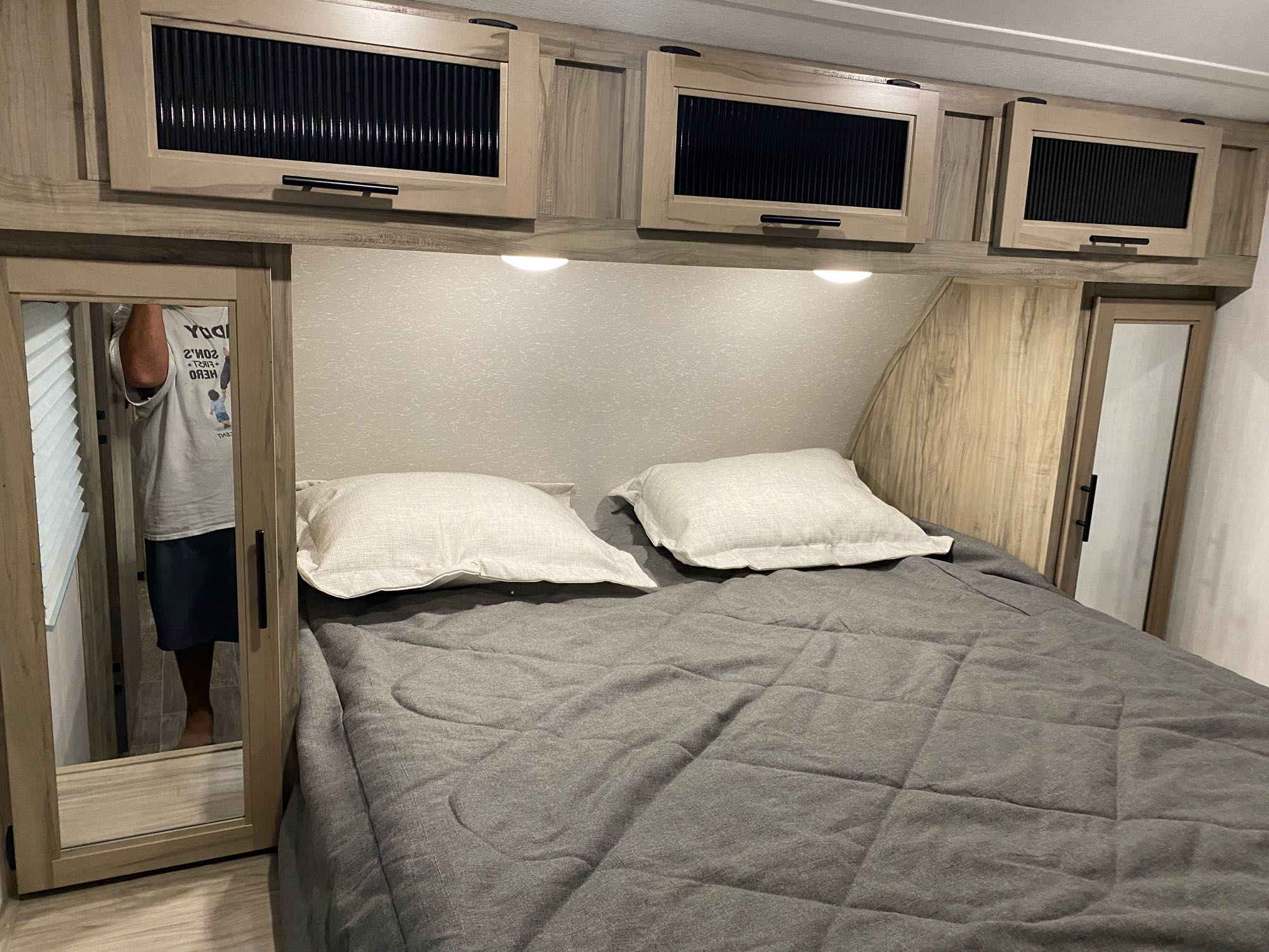 Spacious RV rental bedroom with comfortable bed, overhead storage cabinets, and mirrored closet for a cozy stay.. Forest River Cherokee Alpha Wolf 2021