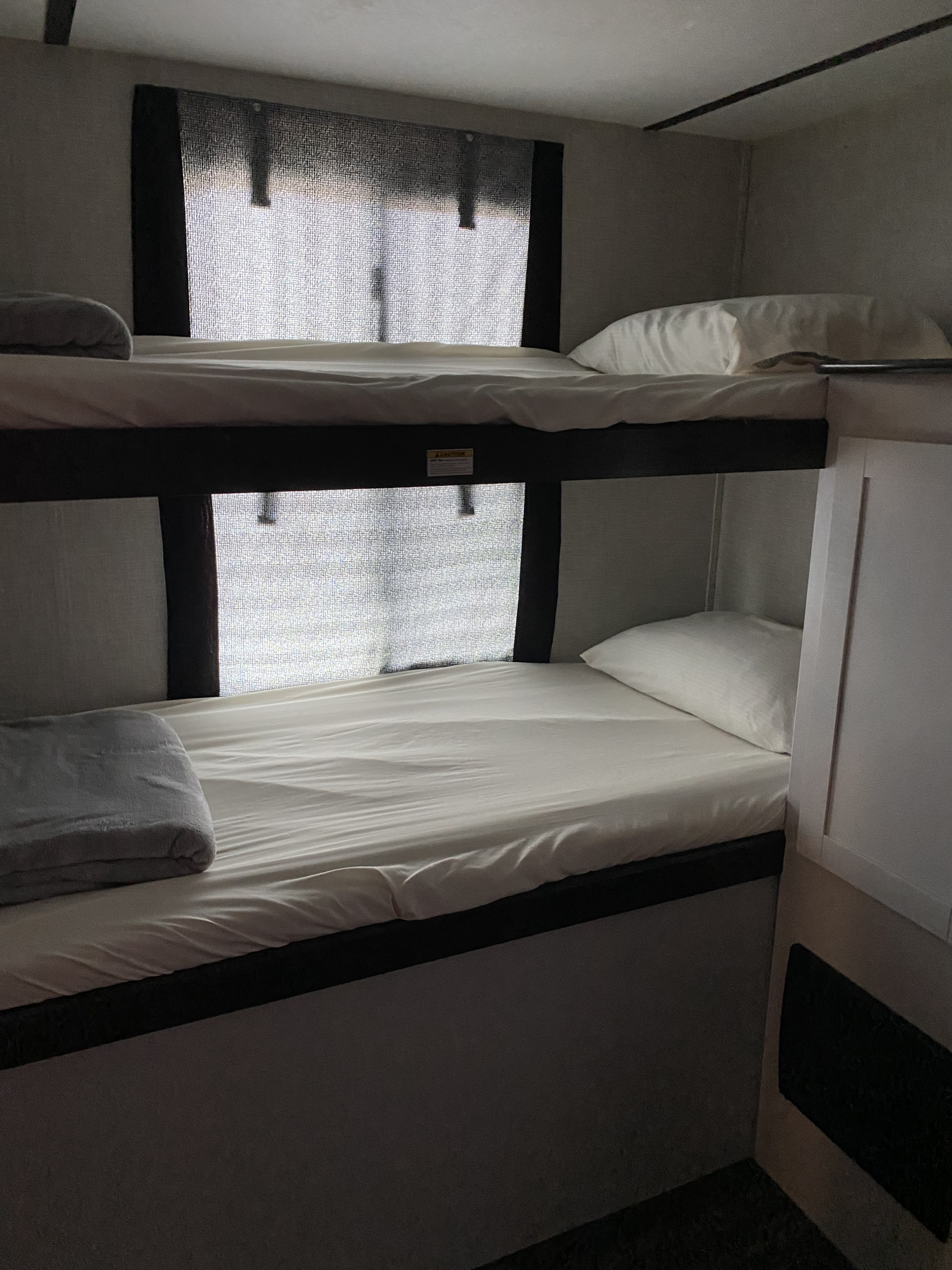 Cozy bunk beds in an RV rental bedroom, featuring white bedding, ideal for family travel.. Keystone RV Bullet Ultra Lite 2021