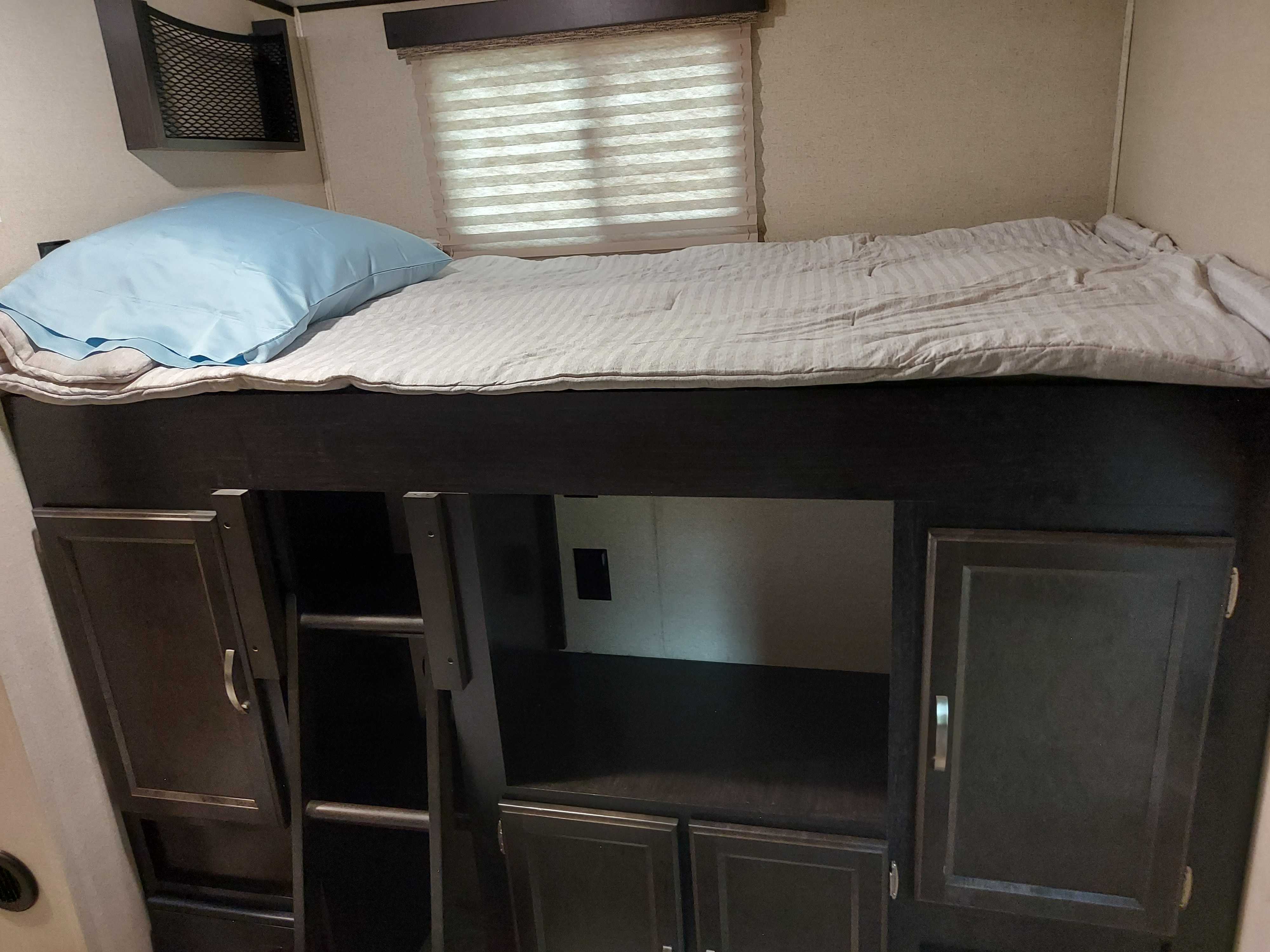 Cozy RV rental bunk bed interior with a striped mattress, blue pillow, window, and built-in storage below.. Coachmen Other 2020