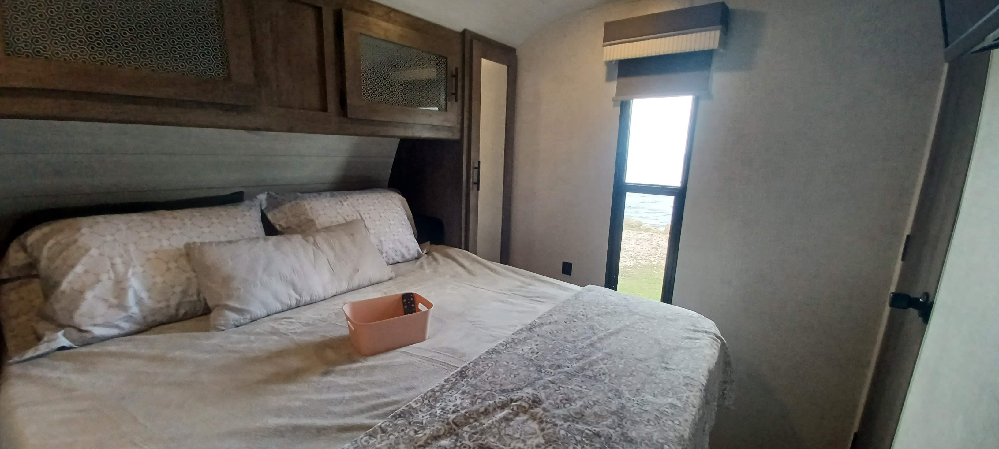 Comfortable RV rental bedroom with spacious bed, overhead cabinets, and a scenic window view.. Forest River Other 2021