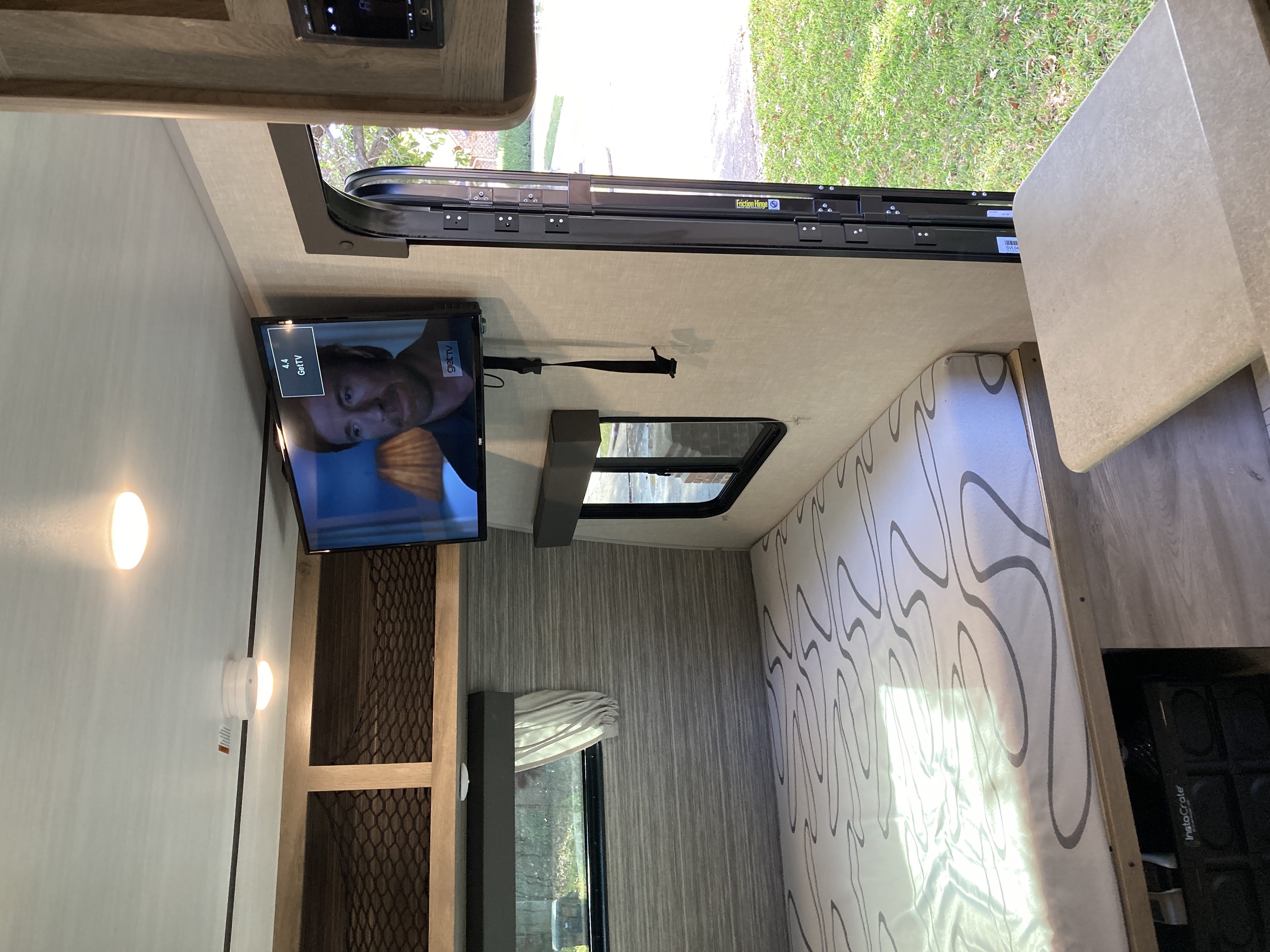 Explore this cozy RV rental interior with a TV, patterned bed, and open door, perfect for your next adventure.. Forest River Surveyor Legend 19BHLE 2022