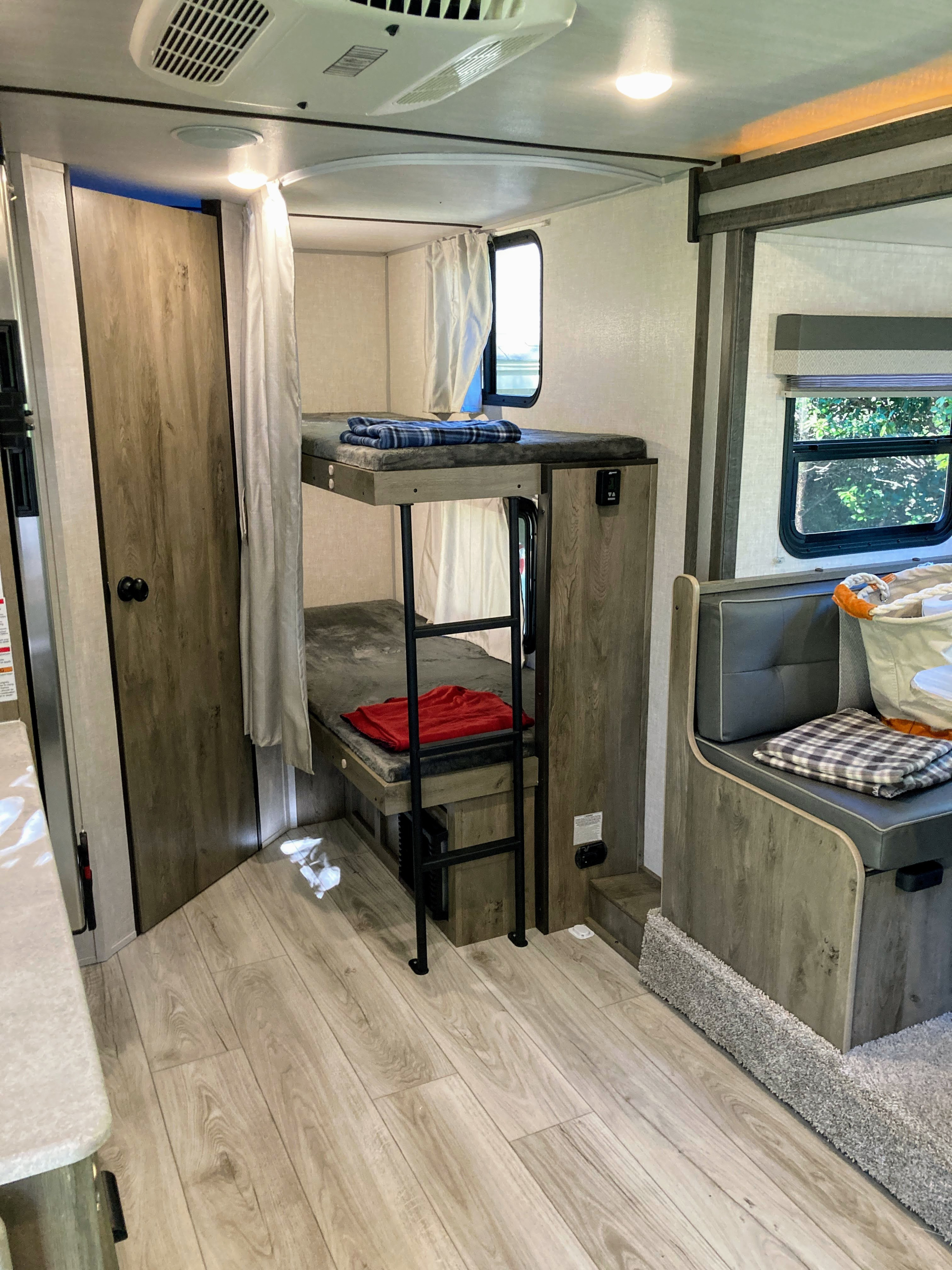 Spacious RV rental interior with bunk beds, a cozy seating area, and light wood finishes in a modern camper design.. Forest River Surveyor Legend 19BHLE 2022