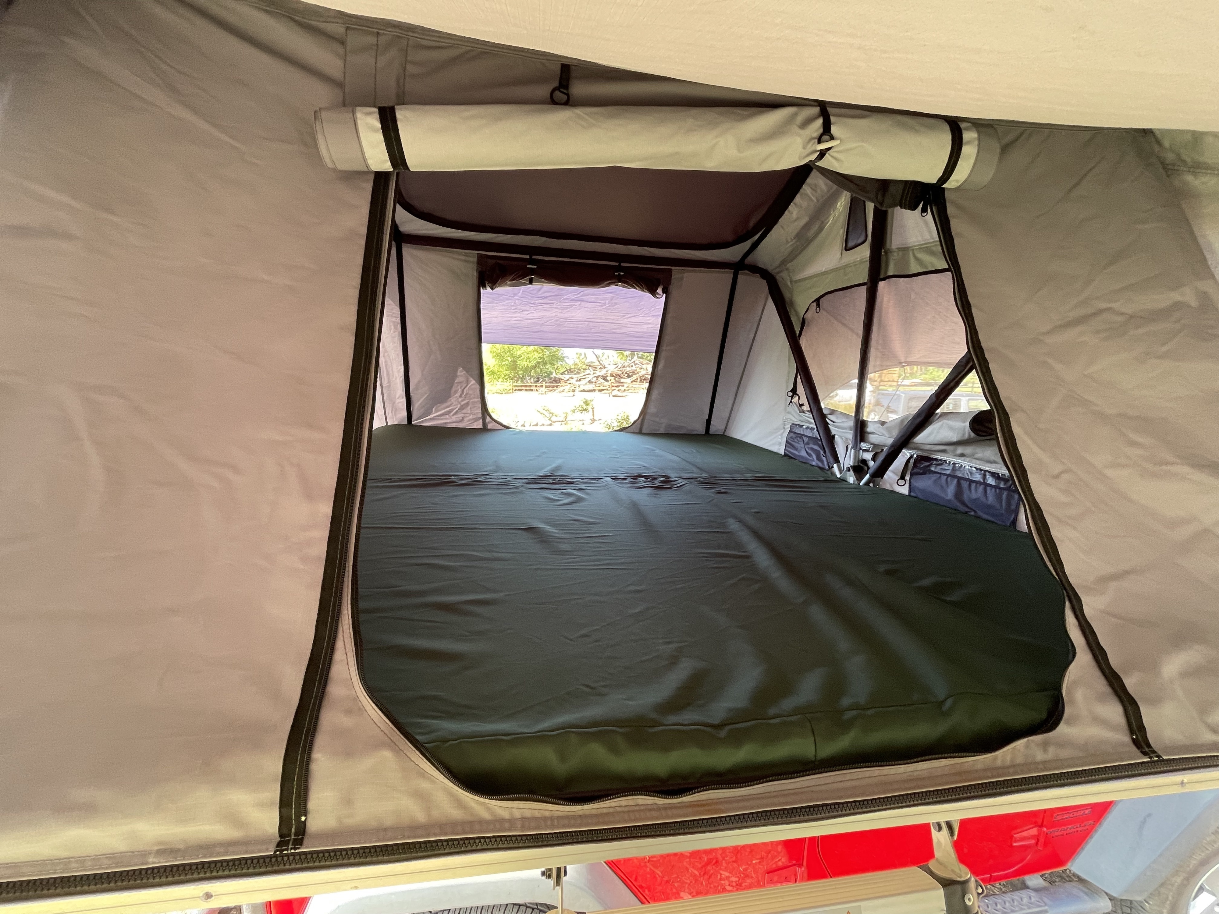 Comfortable interior of a rooftop tent with a mattress and open windows, ideal for an RV rental camping adventure.. Jeep Wrangler 2016