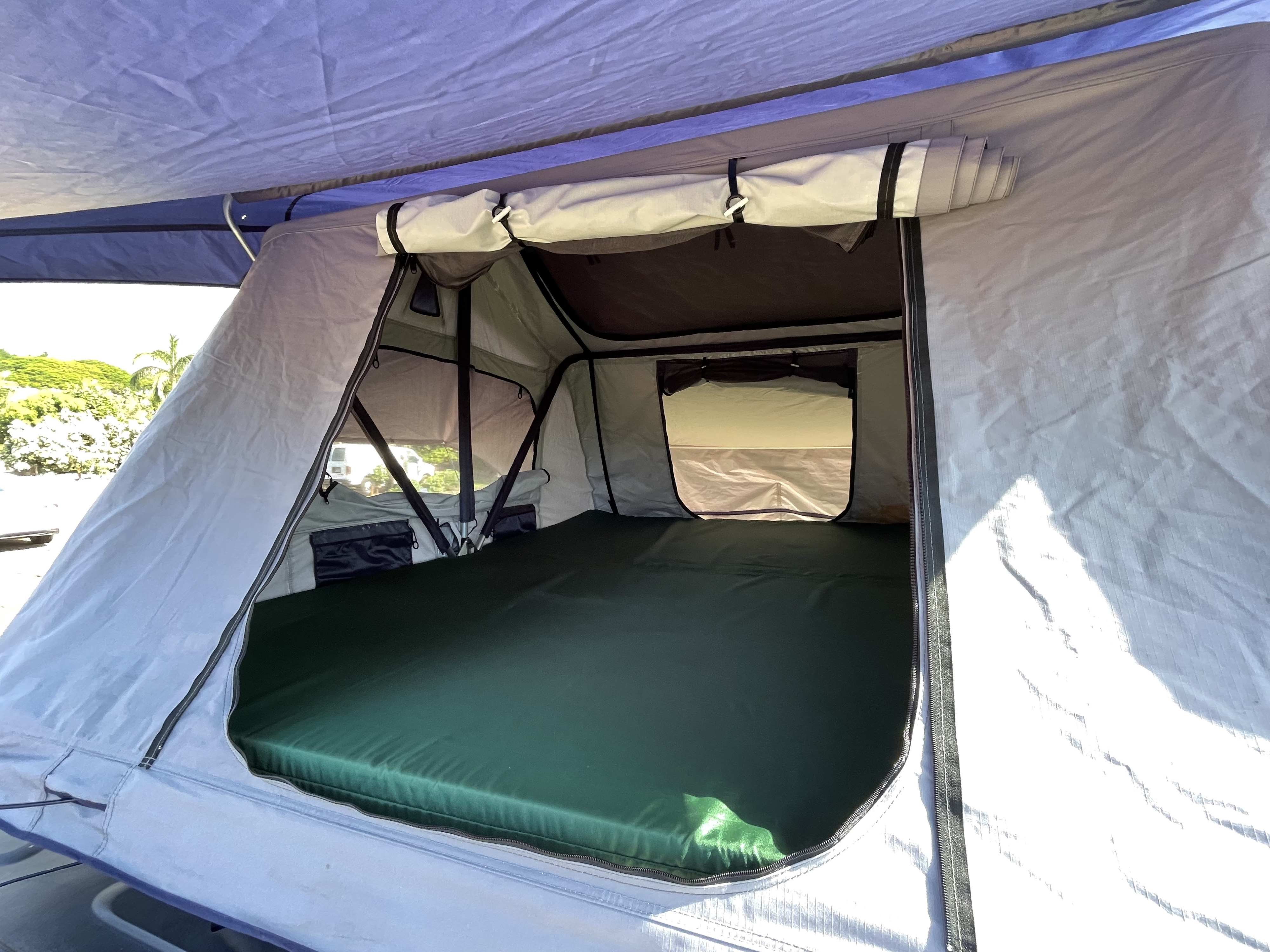 Inside a comfy RV rental rooftop tent, showing the green mattress and spacious sleeping area for adventures.. Jeep Wrangler 2016