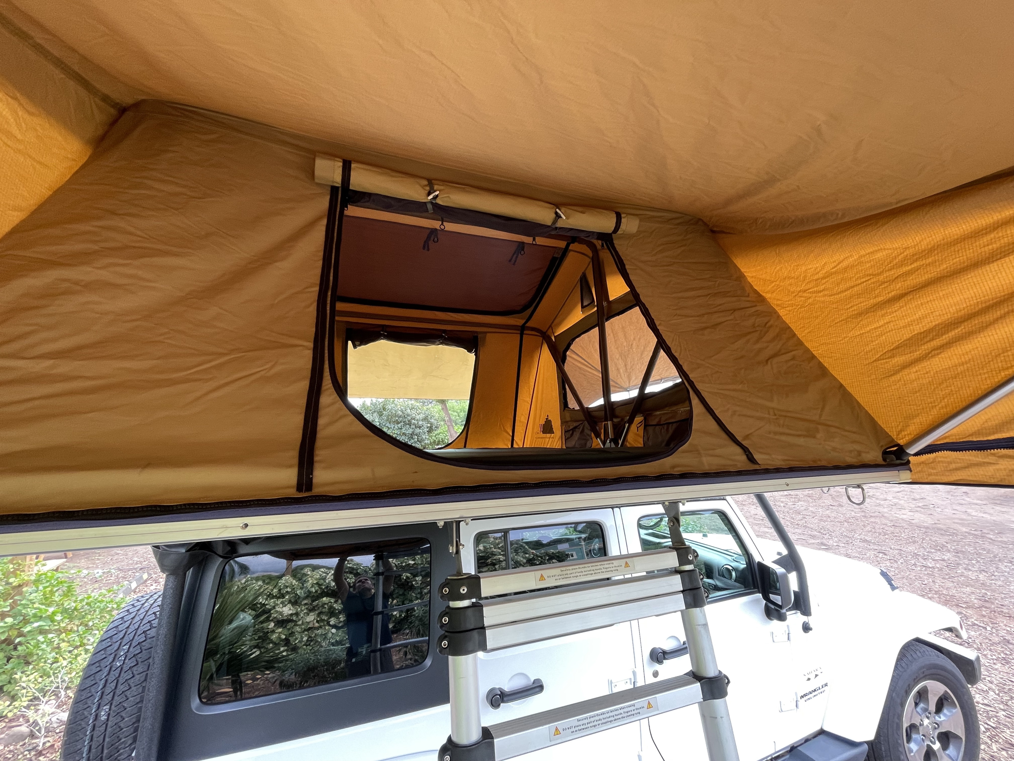 View from below an open rooftop tent on a white Jeep Wrangler, an agile RV rental alternative for overland camping adventures.. Jeep Wrangler 2017