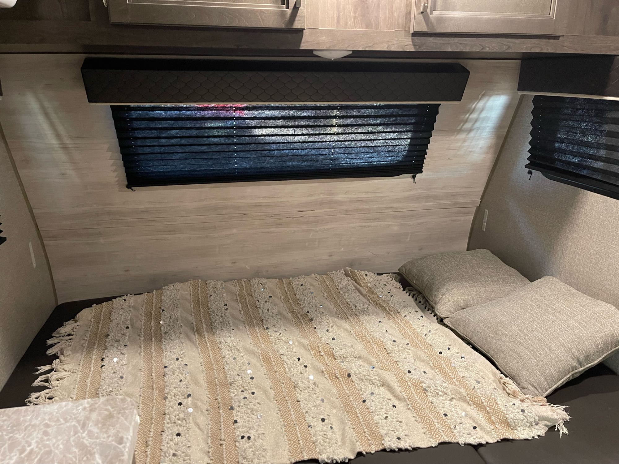 Cozy RV rental bedroom featuring light wood walls, dark blinds, and a bed with a textured, sequined blanket.. Jayco Jay Flight SLX 2021