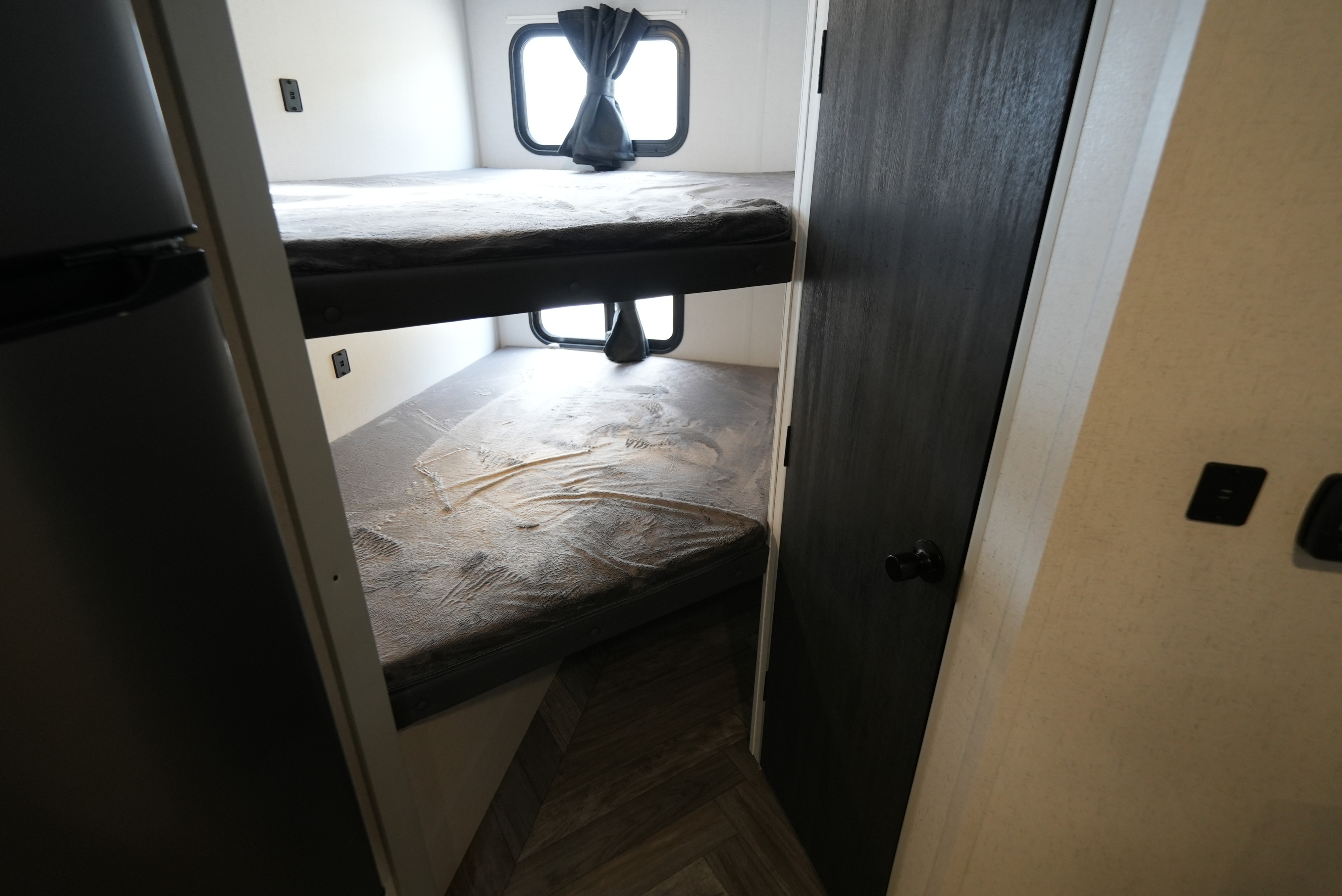 Cozy RV rental bunk beds with windows, providing comfortable sleeping arrangements inside a travel trailer.. Wildwood FSX 178BHSK 2022