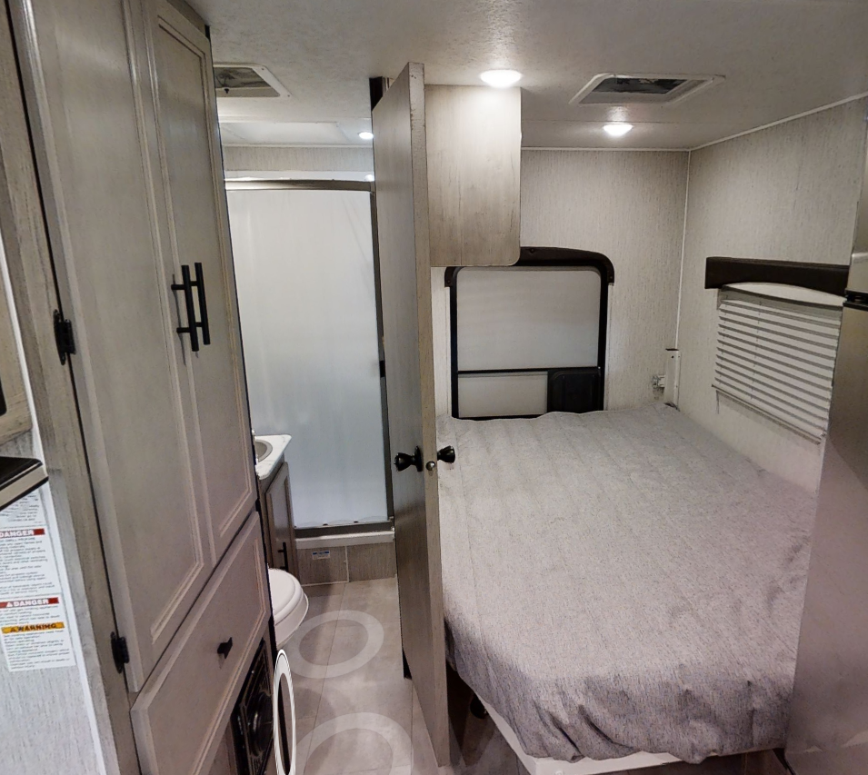 Inside an RV rental: a compact layout featuring a comfortable bedroom with a bed and a convenient bathroom with a shower.. Forest River Coachmen Freelander 2022
