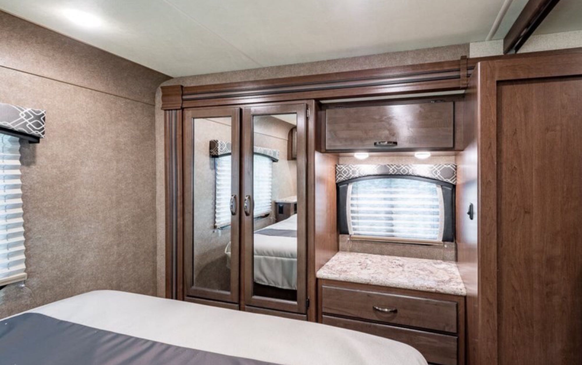 This inviting RV rental bedroom features a comfortable bed, mirrored closet, and practical storage solutions.. Thor Motor Coach Chateau 2020