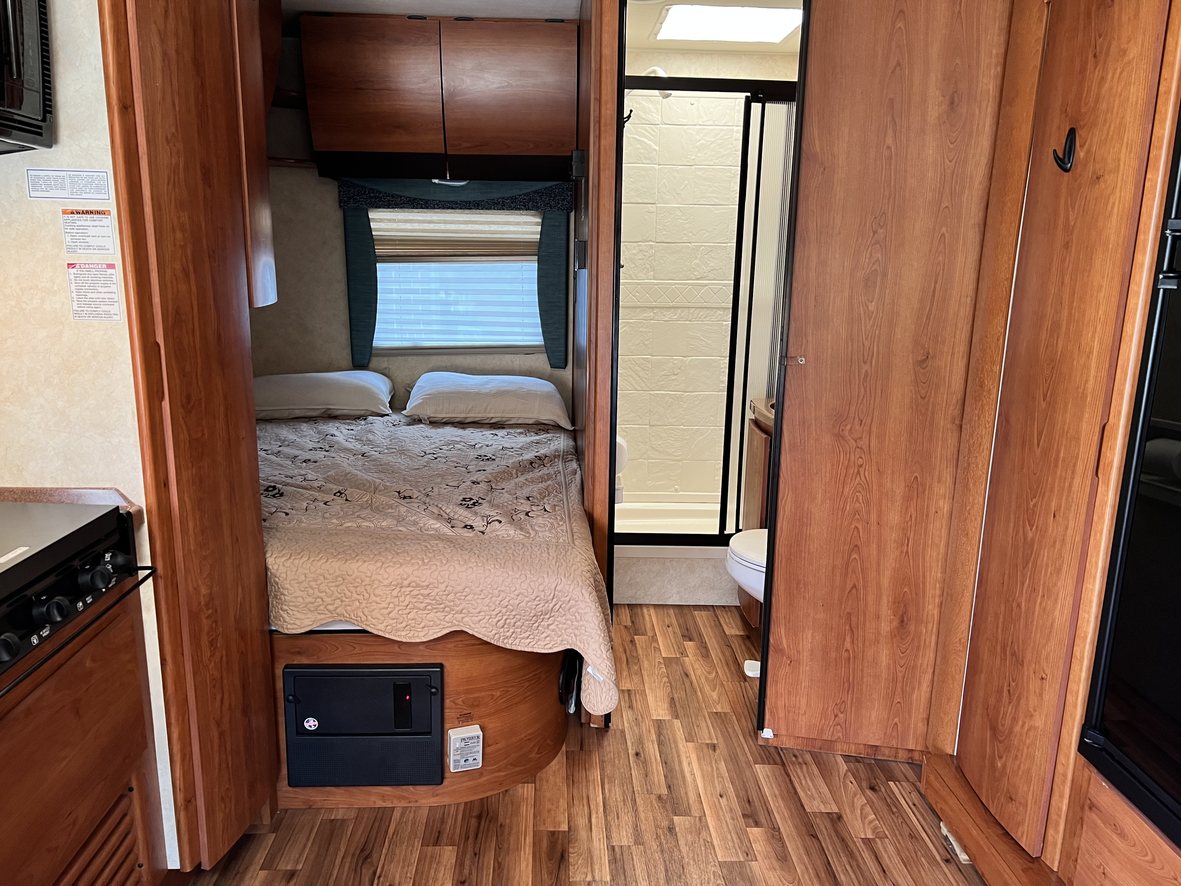 View inside an RV rental showing a comfy bedroom, compact shower, and kitchen. Ideal for adventure travel.. Winnebago Mercedes 2012