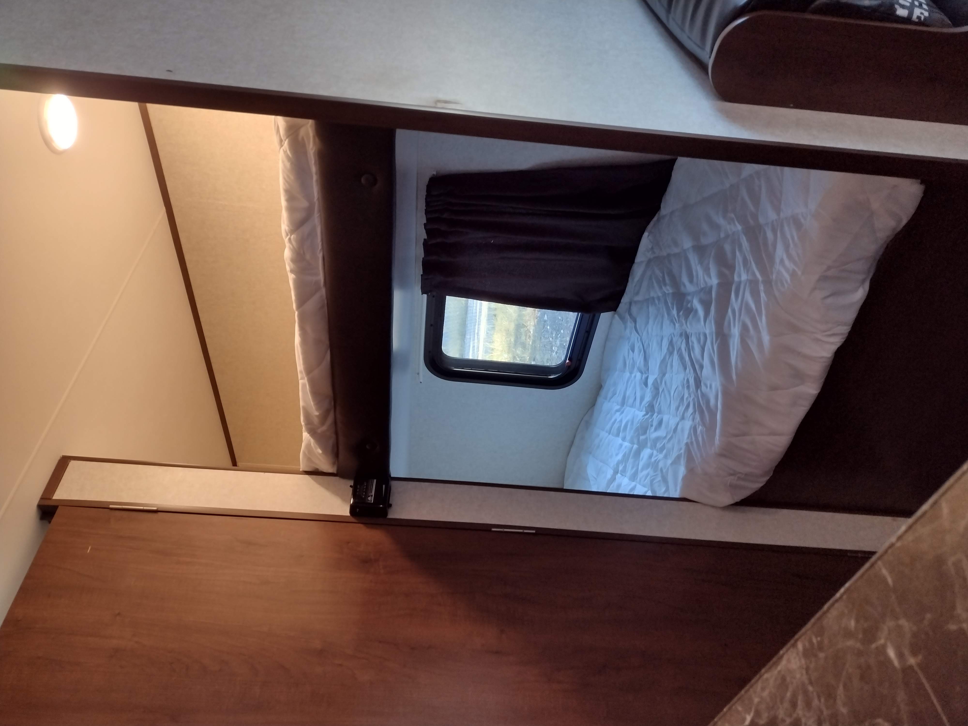 View inside an RV rental shows a lower bunk with white bedding, a window with a dark blind, and an upper bunk.. Jayco Jay Flight 2017