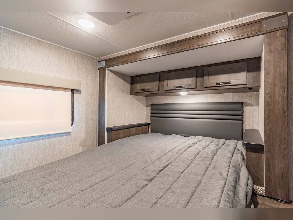 Cozy RV rental bedroom featuring a comfortable bed, padded headboard, overhead storage, and a window. Perfect for travel.. Other Other 2022