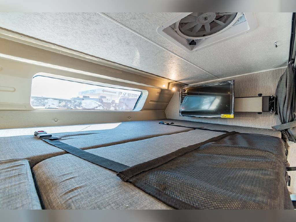 Inside an RV rental: a comfortable bunk area with window, TV, and safety straps. Ideal for sleeping or lounging on your trip.. Other Other 2022