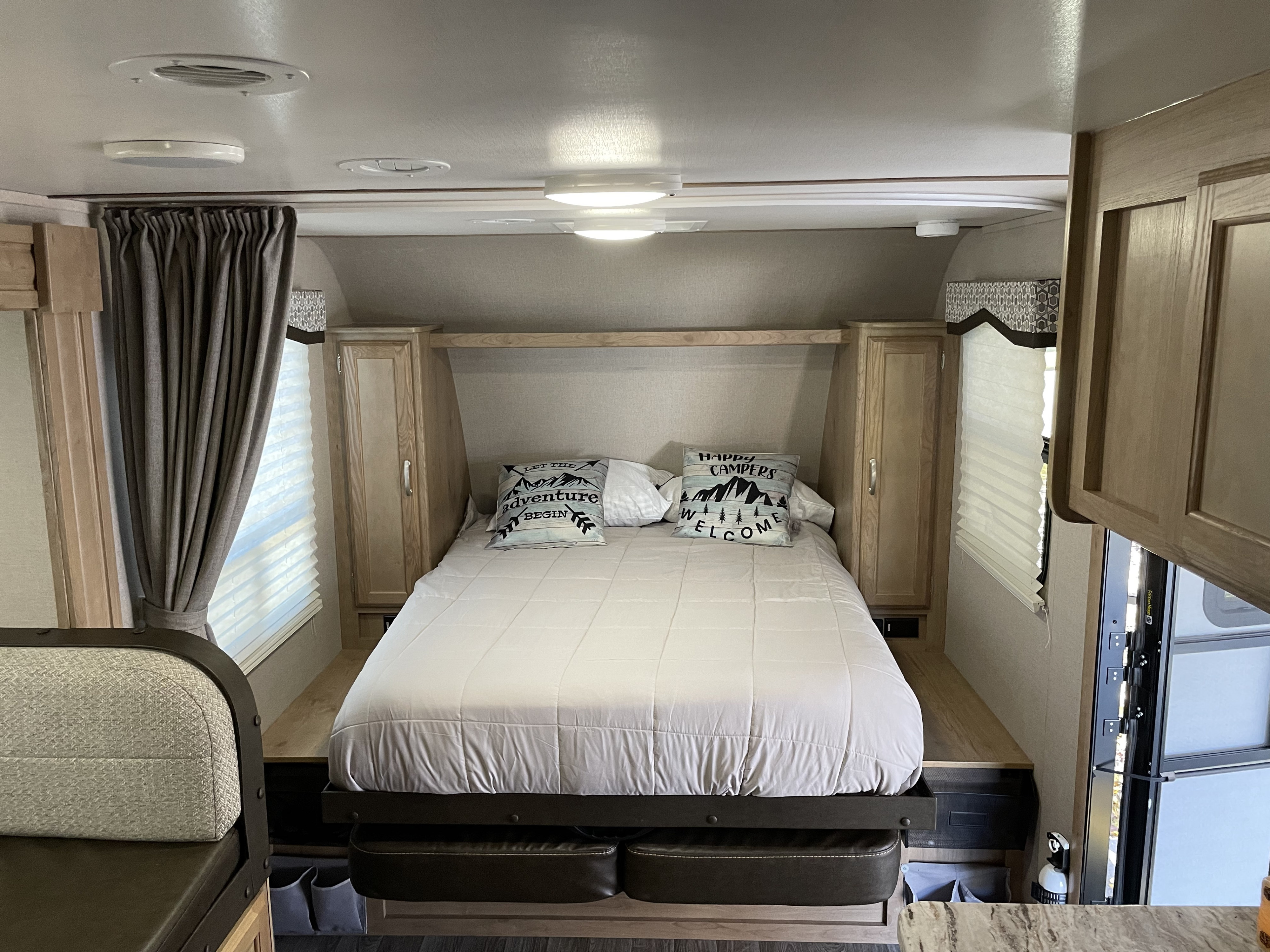 Cozy RV rental bedroom features a queen bed, surrounding cabinets, and light wood interior, ideal for travel.. Winnebago Micro Minnie 2020