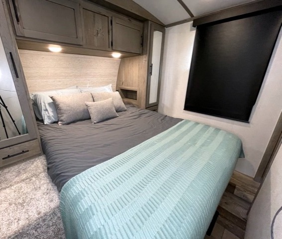 Comfortable RV rental bedroom with spacious bed, overhead storage, and modern decor. Perfect for your next adventure.. Keystone RV Outback 2021