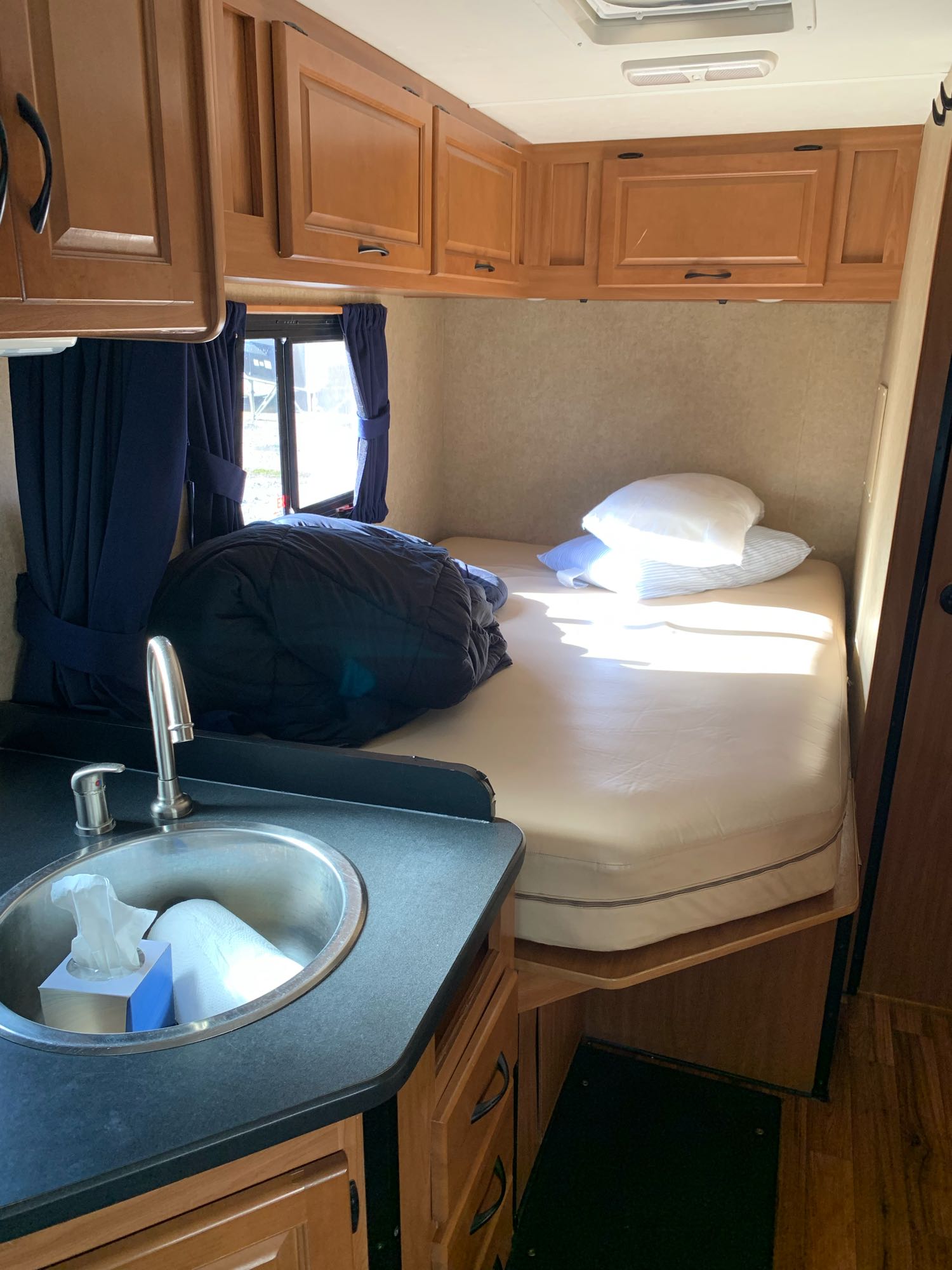 View inside an RV rental, featuring a compact bed area, sink, and functional wood cabinetry.. Thor Majestic 2017
