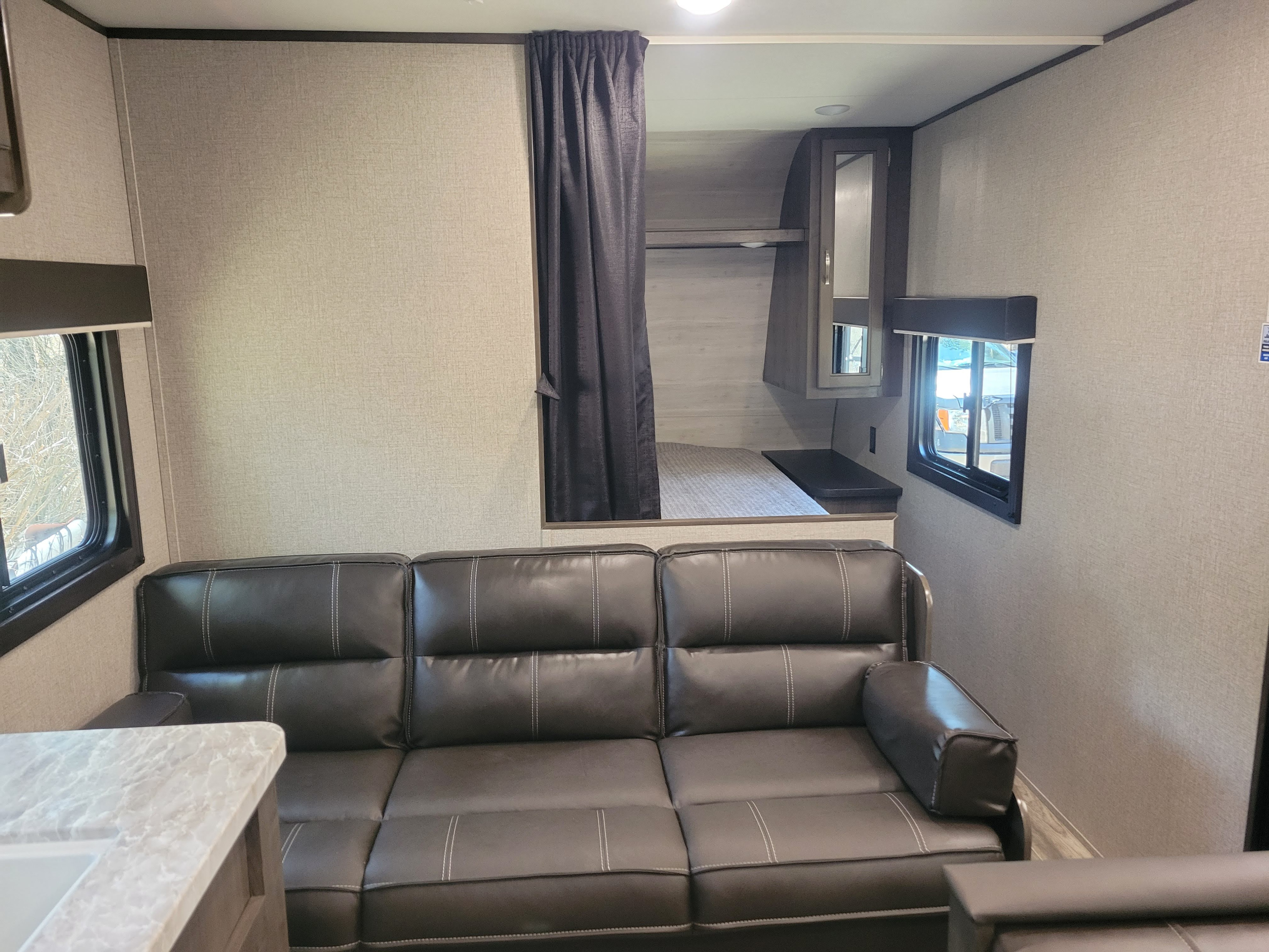 RV rental interior: a dark sofa with white stitching, bunk bed, mirrored cabinet, and windows. Ready for your next trip.. Jayco Jay Flight 2021