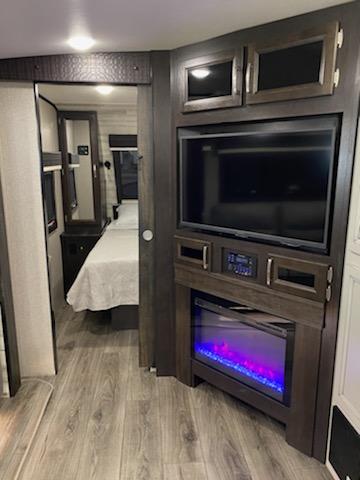 Explore your next RV rental: A modern RV interior with a sleek entertainment center, fireplace, and spacious bedroom.. Jayco White Hawk 29BH 2021