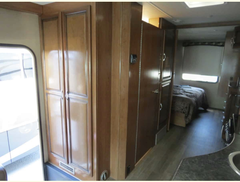 RV rental interior: Wooden cabinets, a cozy bedroom with a window, and a glimpse of the kitchen counter.. Fleetwood Other 2018
