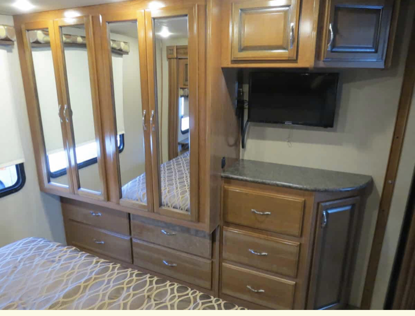 Inside an RV rental: a compact bedroom with a bed, mirrored wardrobe, drawers, and TV.. Fleetwood Other 2018
