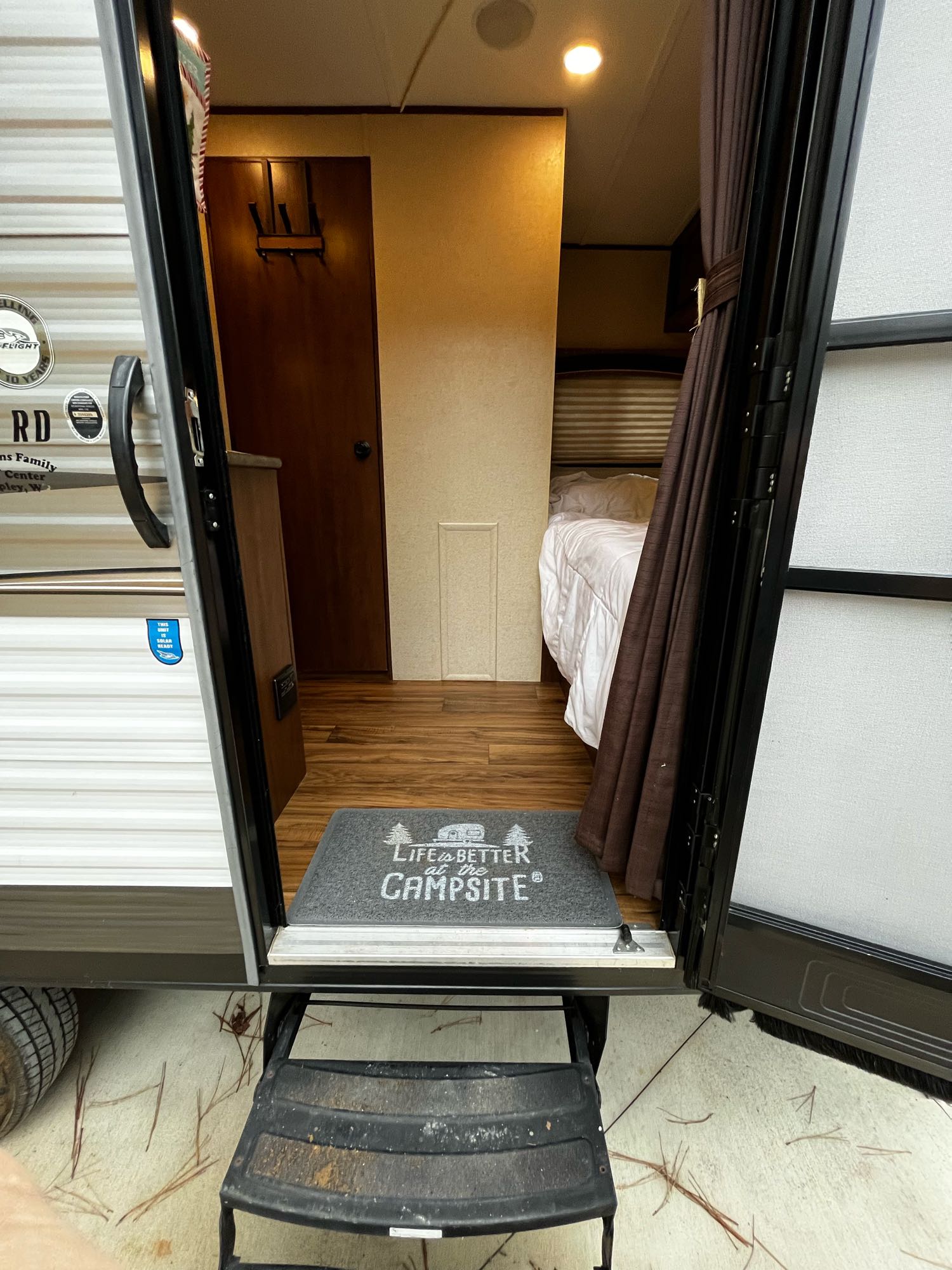 Stepping into a comfortable RV rental, featuring an inviting interior and "Life is Better at the Campsite" doormat.. Heartland Jay Flight 2016