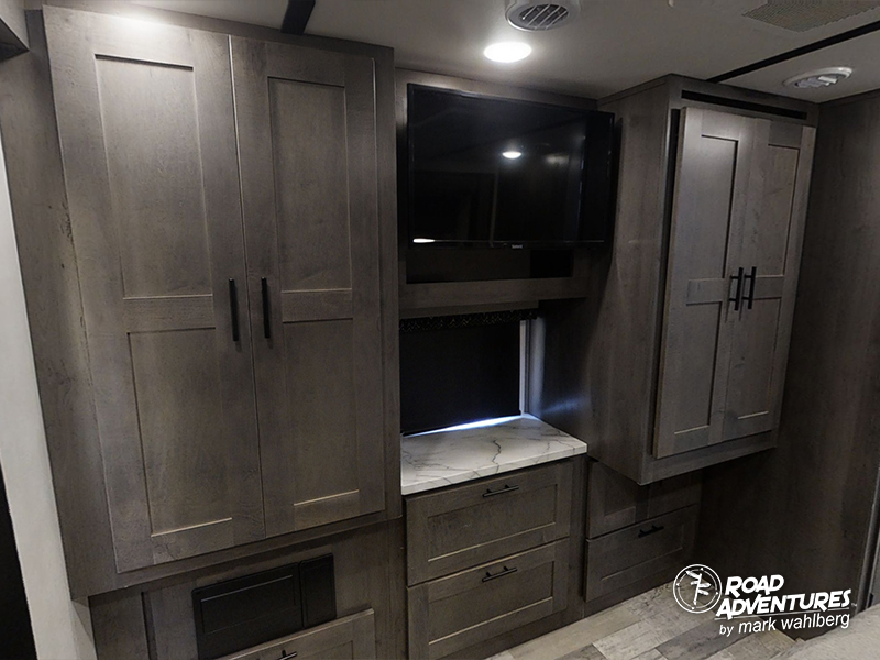 Modern RV rental interior with dark wood cabinets, TV, and counter. Functional storage for road adventures.. Forest River Fr3 2021