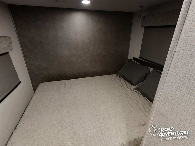 Compact RV rental bedroom with a cozy bed, dark walls, and light bedding. Ideal for road adventures.. Forest River Sunseeker 2022