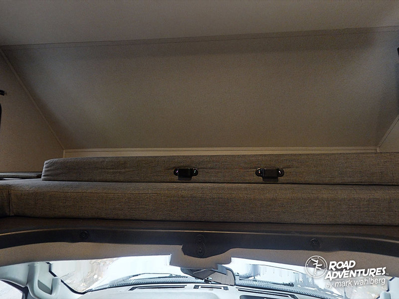 Cozy cab-over bunk in an RV rental, complete with gray cushions and secure latches.. Forest River Sunseeker 2022