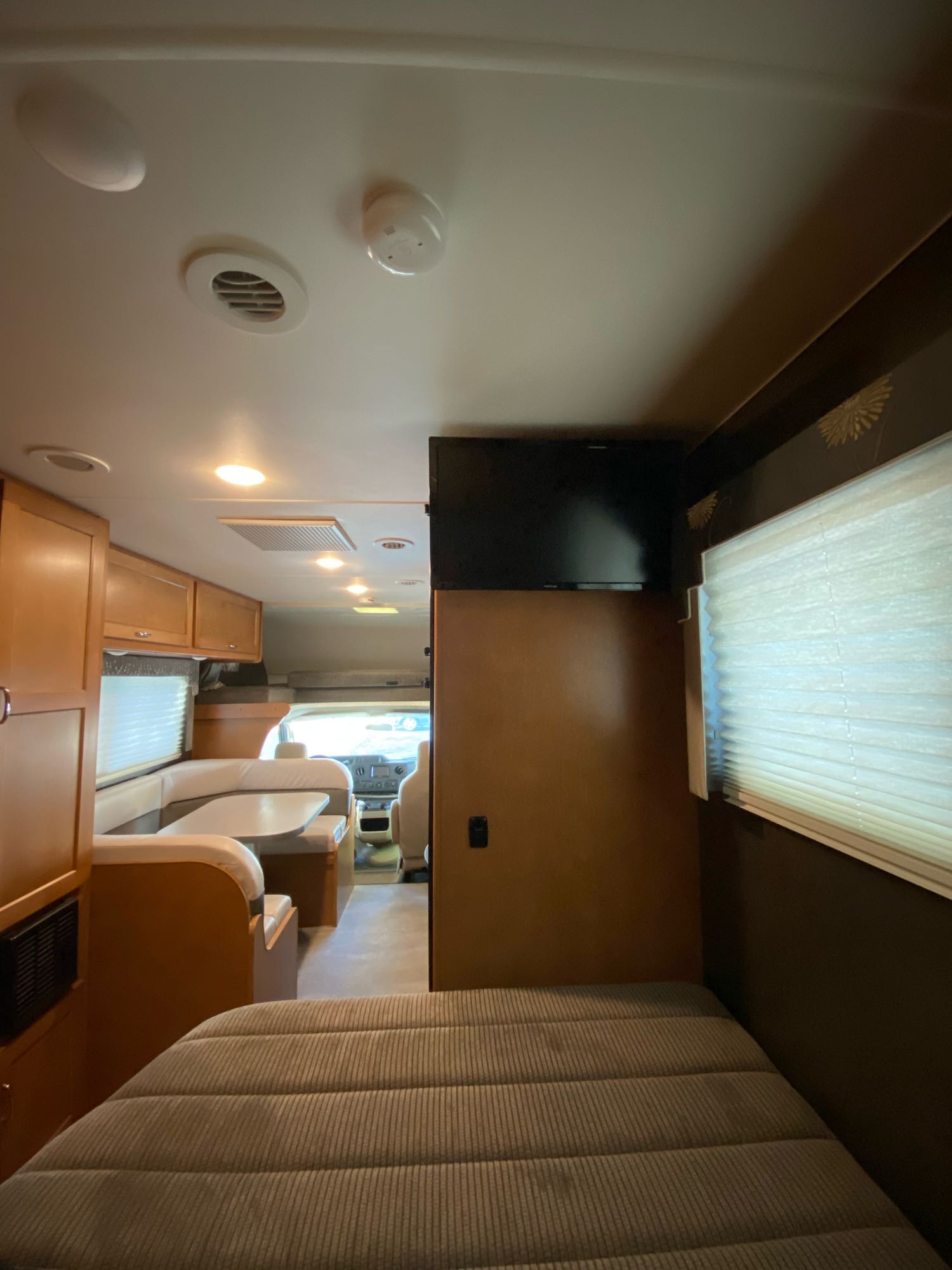 This RV rental features a cozy interior: bed in foreground, dining area, kitchen, and driver's cabin beyond.. Winnebago Minnie Winnie 2018