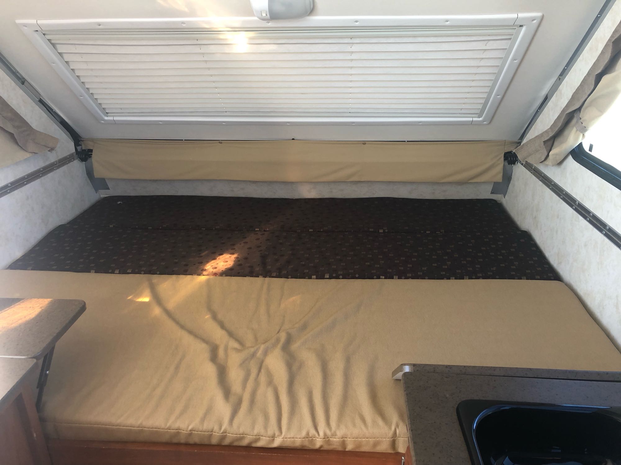 Comfortable RV rental interior: spacious bed, overhead blinds, & kitchenette area for your next adventure.. A Liner A Liner Popup Trailer 2014